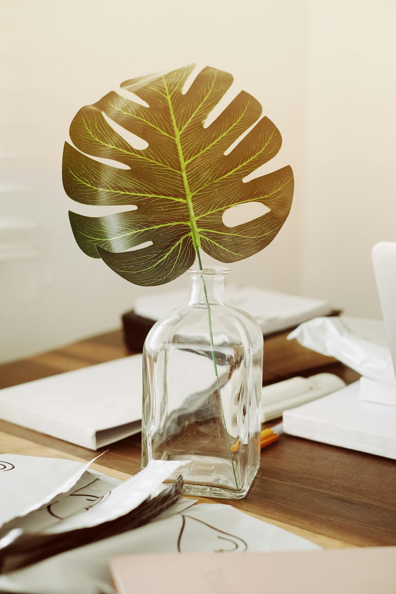 Elegant minimalist decor with a tropical leaf in a glass vase, perfect for interior design aesthetics.